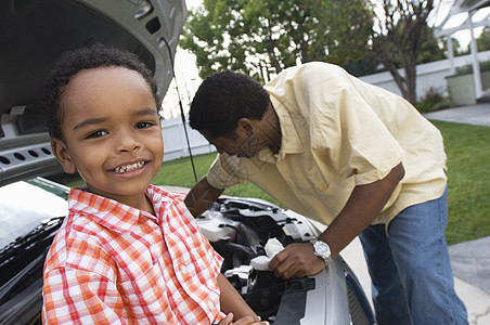 一名小男孩的肖像 男子用背景检查汽车发动机的情况;图片