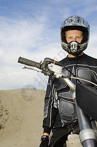 自行车越野在赛马场对天上骑着摩托摩托车骑手的男性离公路机动自行车驾驶者的肖像背景