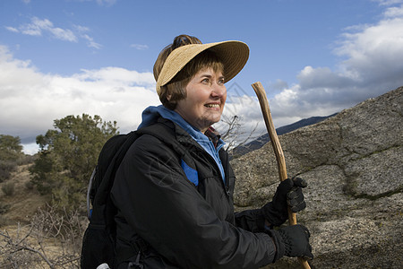 快乐的高级女性登山者 用木棍徒步旅行图片