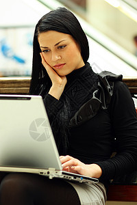 坐在长椅上的美丽的年轻女士电脑商业店铺互联网城市快乐教育女性微笑女孩图片