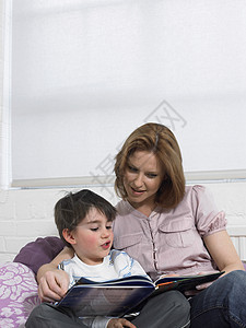 爸爸妈妈和孩子一起在年轻女人和儿子在家床上一起读书的书背景