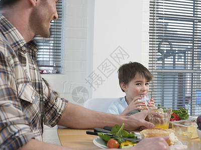 家餐桌上吃饭的可爱男孩和父亲的肖像图片