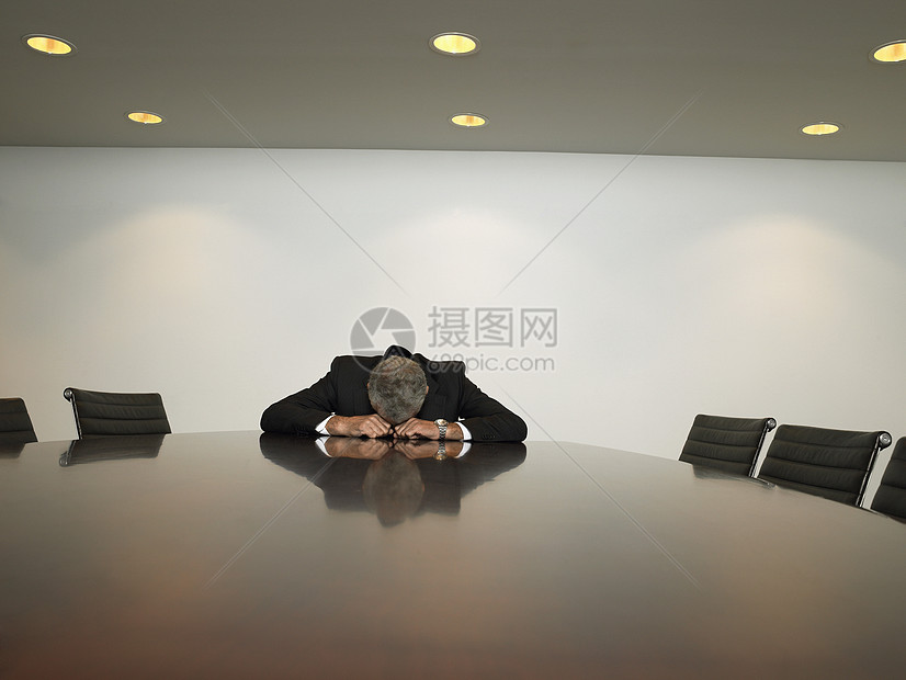 不幸的商务人士在会议室把头放在桌子上休息图片