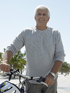 在热带沙滩骑自行车的活跃老年男子图片