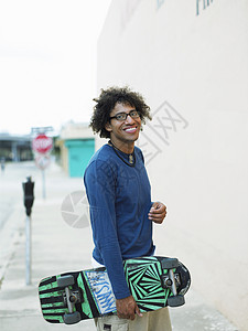 快乐的年轻男子在人行道上玩滑板的肖像图片