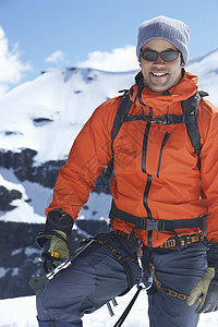 一个微笑的男性登山者的肖像 站在雪山对着雪山图片