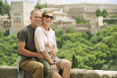 坐在西班牙格拉纳达城墙上的旅游情侣肖像图片