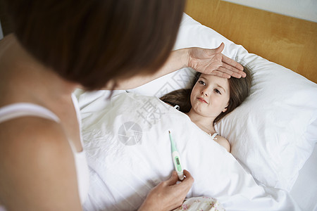 母亲检查在床上有温度计的女儿的体温流感孕产温度疾病羽绒被女士房子测量孩子女孩背景图片