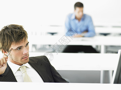 计算机台有深思熟虑的商务人士 背景是男性同事图片