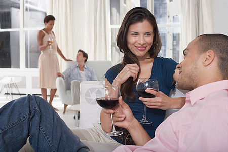 在客厅饮酒的年轻多民族夫妇闲暇享受团体种族团结派对男士微笑社交沙发图片