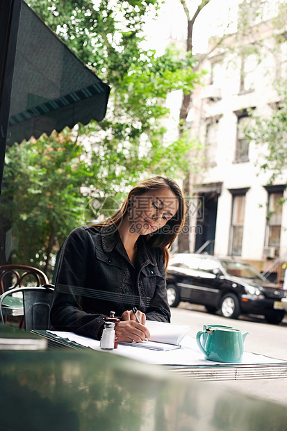 年轻女性在人行咖啡厅写作成人享受闲暇活动街道日记娱乐杂志桌子咖啡图片