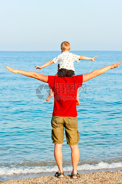 儿子坐在他父亲的肩膀上 他的胳膊在旁边图片