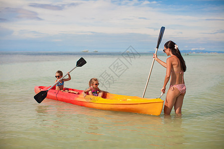 年轻母亲和两个女儿 在蓝色温暖的海中划艇图片