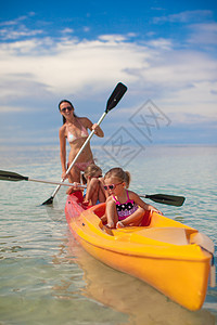 两个小女孩和年轻母亲 在蓝色温暖的海面上划艇图片