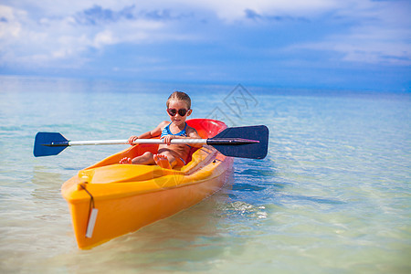 可爱的小可爱女孩 在清蓝的海面上划皮艇旅行活动假期天空乐趣娱乐微笑海洋童年血管图片