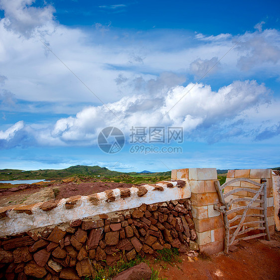 在Menorca带栅栏门的红披萨红色石墙天空草本植物岛屿蓝色国家牧草雏菊植物季节荒野图片