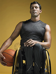 坐在轮轮椅上持篮球的瘫痪运动员图片