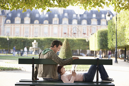 城市公园长椅上轻松的年轻夫妇阅读书图片