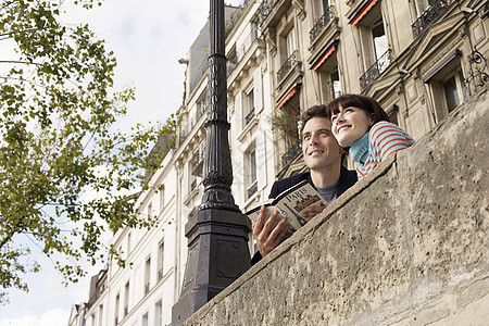 从低角度看一对微笑的情侣 带着指南在桥上看着男人空闲城市旅游公寓夫妻游客快乐观光假期图片