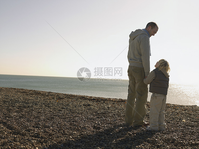 父亲和儿子在海滩上互相看对方的长大图片