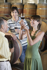 三个人在地下室的酒桶边喝葡萄酒图片