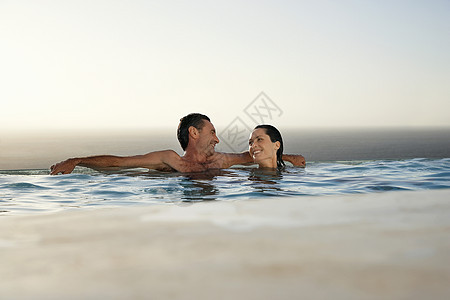 快乐的情侣在度假胜地放松无尽游泳池图片