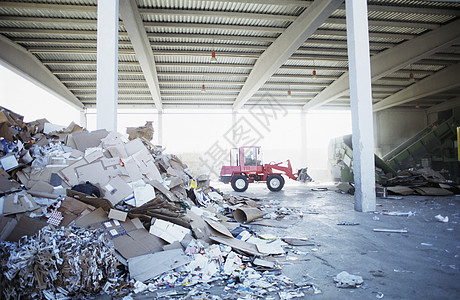回收厂背景的废纸废物堆积物 装有挖掘卡车图片