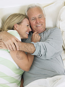 一对快乐的中年夫妇 拥抱在床上的高视图片