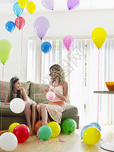 女孩和妈妈坐在沙发上 在满是气球的房间图片