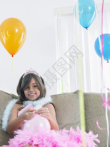 在沙发上微笑的年轻女孩 准备生日气球庆典快乐房间长椅孩子们房子女性孩子童年羽毛图片