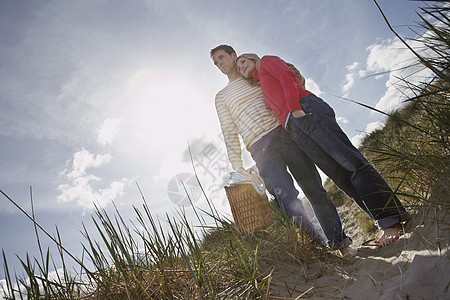 全身情爱的情侣 手在沙丘上握着野餐篮子图片