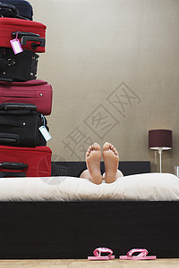 低层妇女躺在一堆手提箱旁边的床下图片