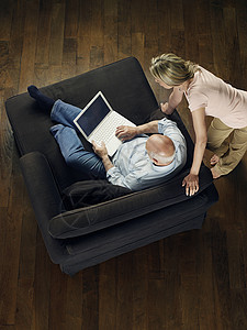 观看成年秃头男子的妇女的顶端视线是在家里沙发上使用笔记本电脑场景互联网成人家具人员夫妻秃顶房子空闲地面图片