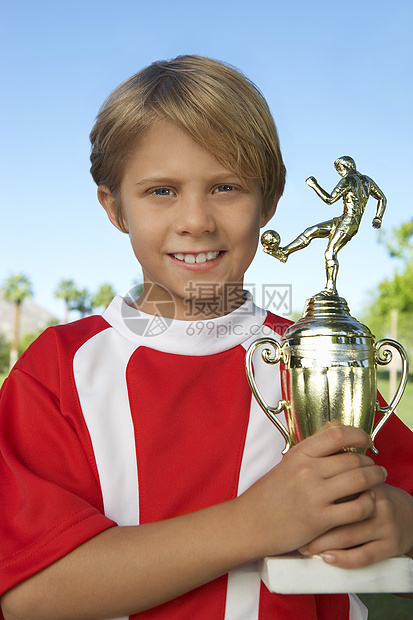 年轻男孩骄傲地拿着足球奖杯的肖像
