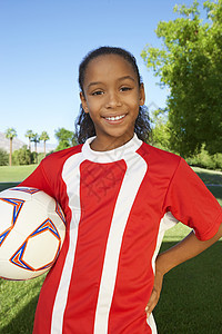 快乐的年轻女孩在田野上踢足球的肖像图片