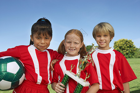 3名儿童在田野上拿着足球球和奖杯的肖像图片
