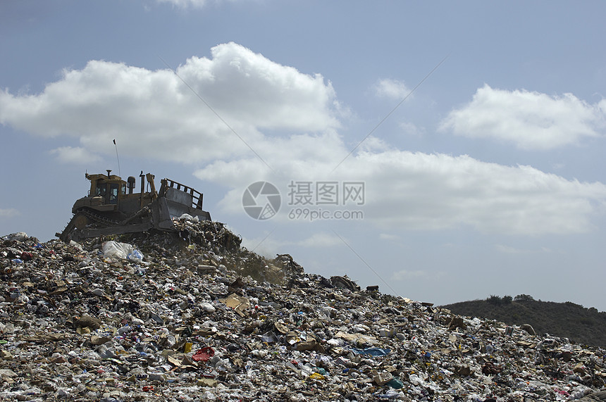 倾弃地对云层天空倾弃的挖土机装载车低角度视图图片