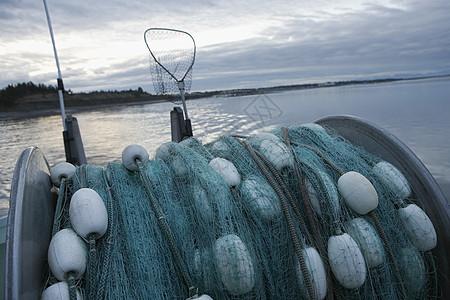 黄昏时一艘渔船背面的商业渔网图片