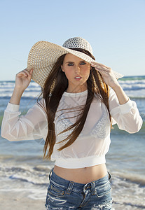 在沙滩上戴帽子的女人腹部衬衫乐趣棕褐色黑发女孩旅行孤独微笑海浪图片