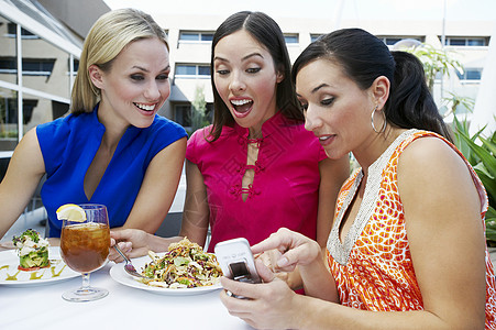 多族裔女性朋友在餐厅的手机上阅读短信 包括多种族女性朋友图片
