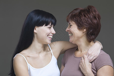 年轻女性拥抱母亲的片场肖像家长幸福妇女微笑头肩成年女儿影棚头发棕色图片