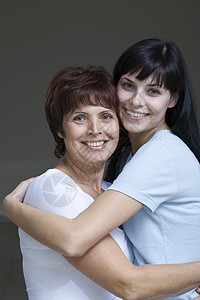 年轻女性拥抱母亲的片场肖像团结幸福友谊头发成年妇女中年微笑家长女儿图片