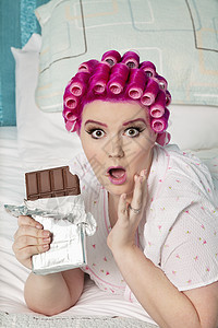 在床上躺着巧克力的震惊女人的肖像图片