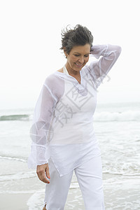 风吹在水边穿白衣的女年长女子头发短发衬衫退休成人一人海滩白色淡季女士背景
