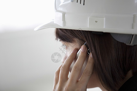 使用移动电话的女商务人士沟通手机防护头饰安全帽仓库人类背景图片