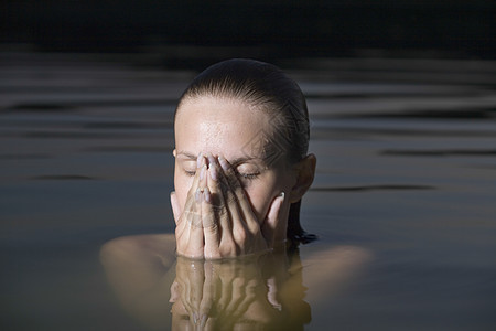 年轻女人用手在水中蒙面图片