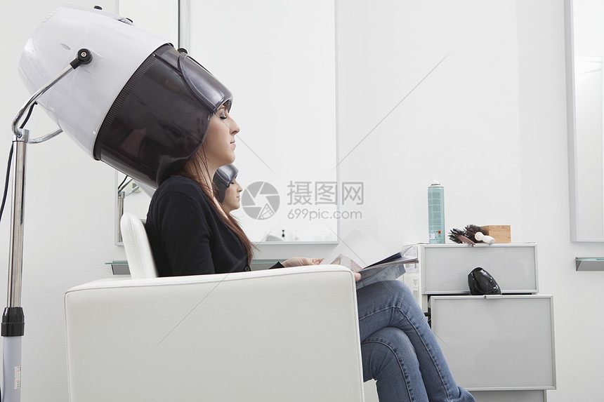 女客户在理发厅坐在干衣帽下图片