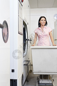一位快乐的中年成年女子在洗衣房推推车的肖像图片