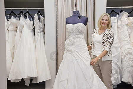 一个快乐的高级女性 调整婚纱的肖像 在新娘店的模特儿上图片