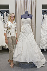 一个快乐女人的肖像 穿着优雅的新娘礼服站在商店里图片